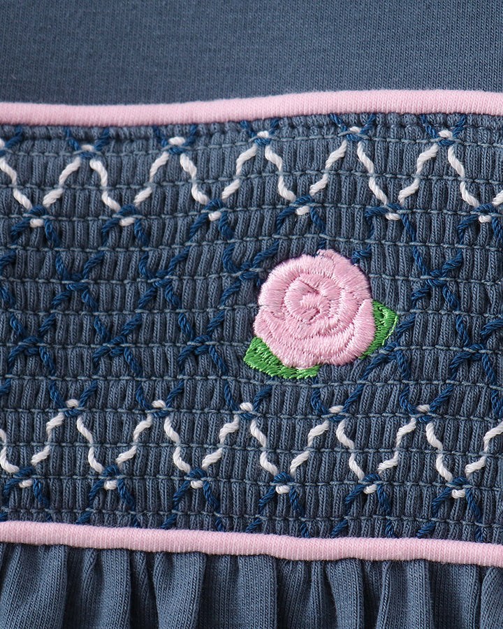 Dark blue smocked bodice with pink trim and small pink flower applique