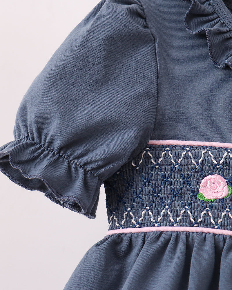 Dark blue ruffled sleeve top with smocked waistband and embroidered rose details