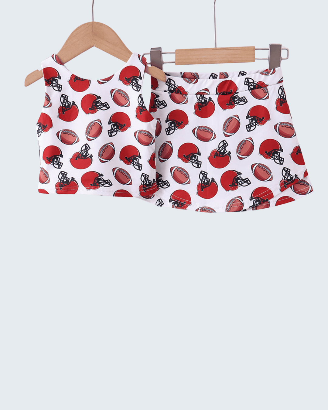 Red and black helmet patterned girls outfit on hangers against a white background