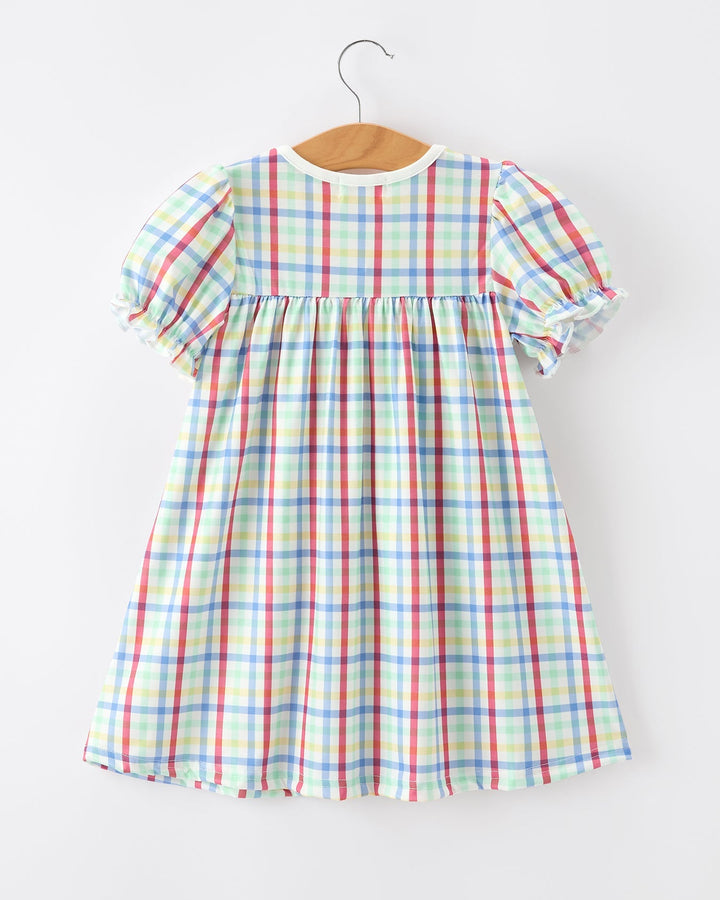 Colorful plaid dress on a hanger against a white background