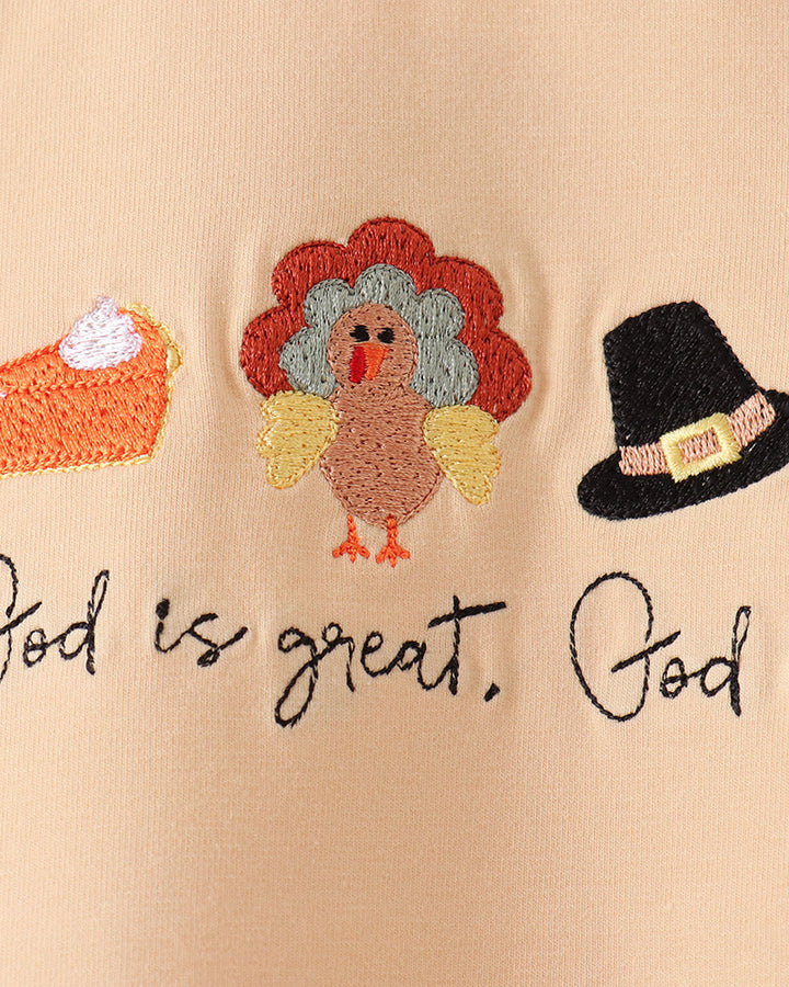 Beige T-shirt close-up with colorful animal embroidery and dark script graphic