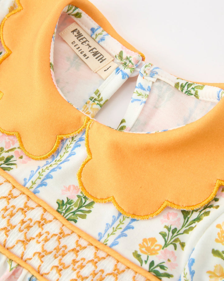 Baby girl dress neckline close-up: scallop orange collar with floral print trim