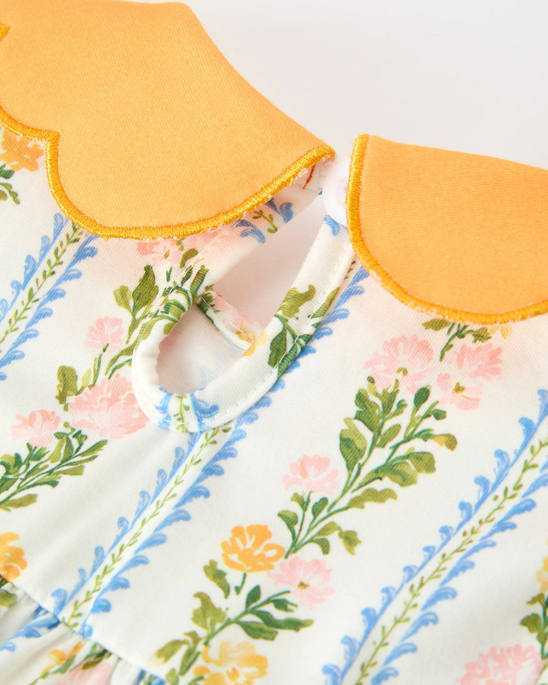 Floral striped baby girl dress close-up of scallop orange collar at neckline