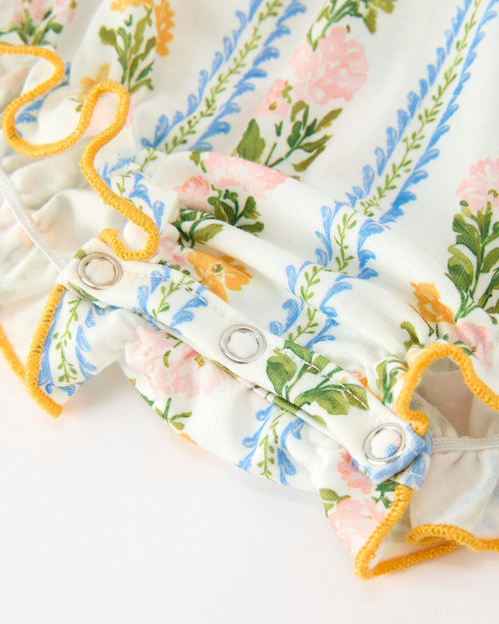 Close-up of floral stripe romper with snap buttons and orange scalloped trim at leg.
