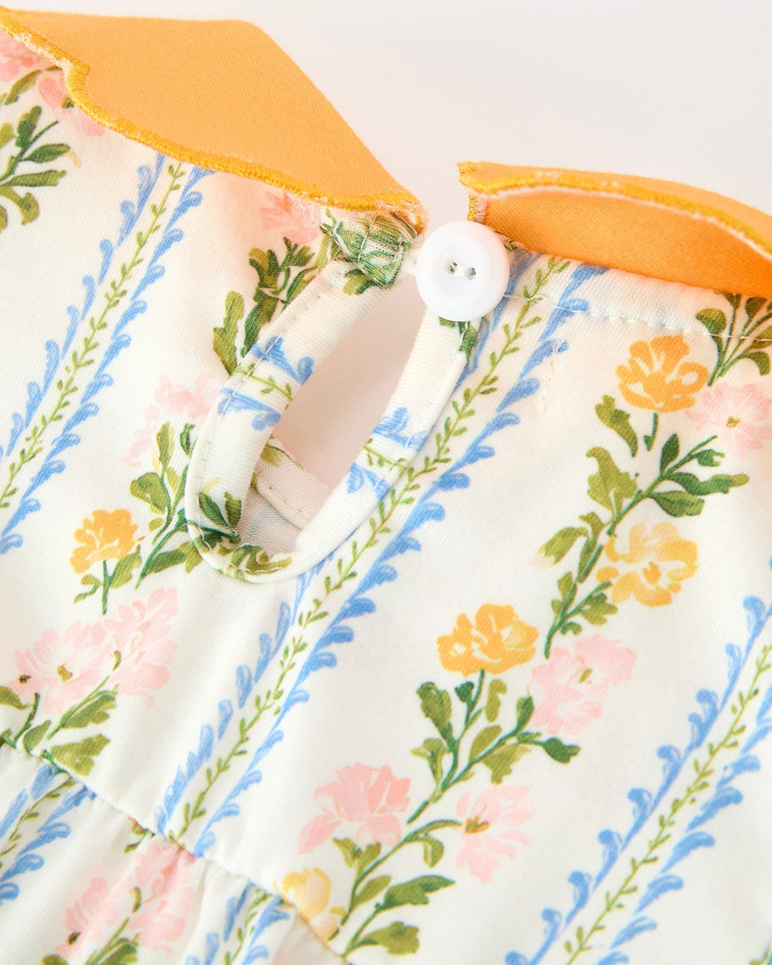 Floral stripe baby romper with orange scalloped neckline and white button placket.