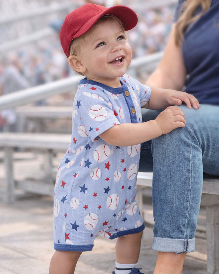 Light blue baseball-print henley romper with navy cuffs and button placket
