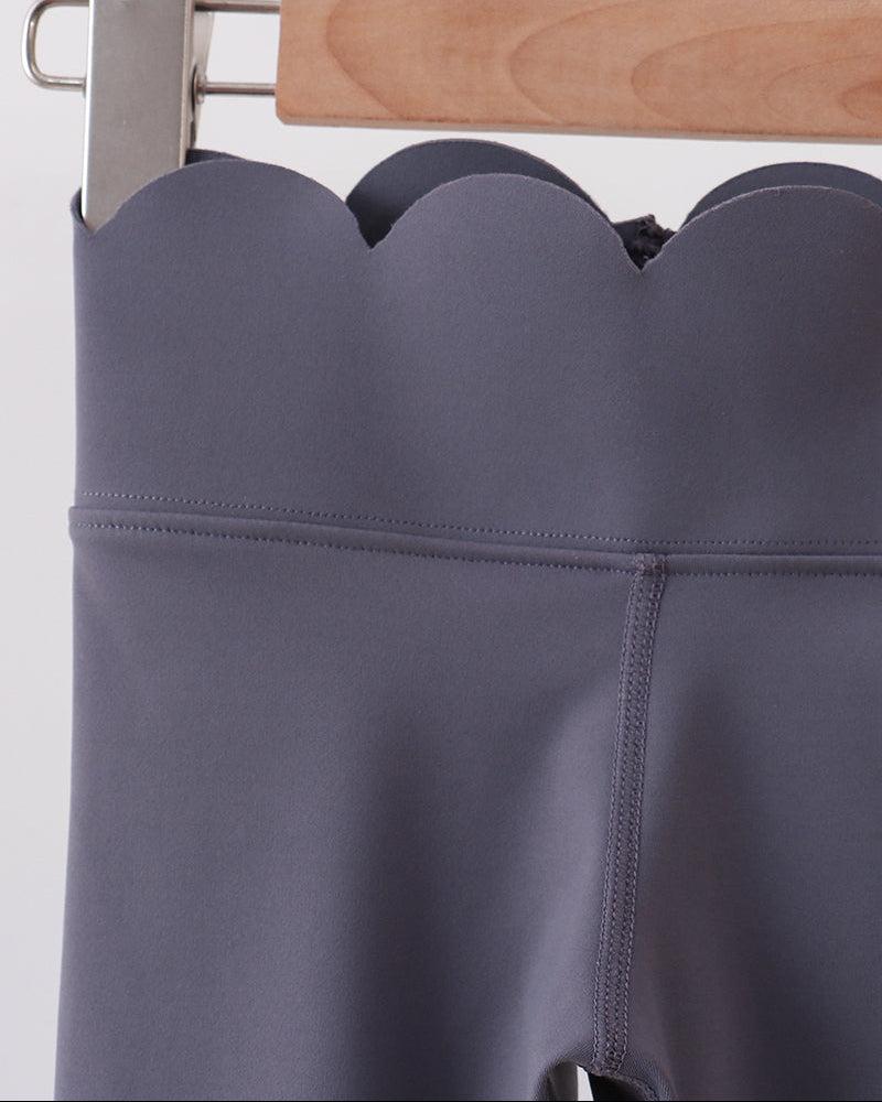 Gray leggings on a wooden hanger against a white background