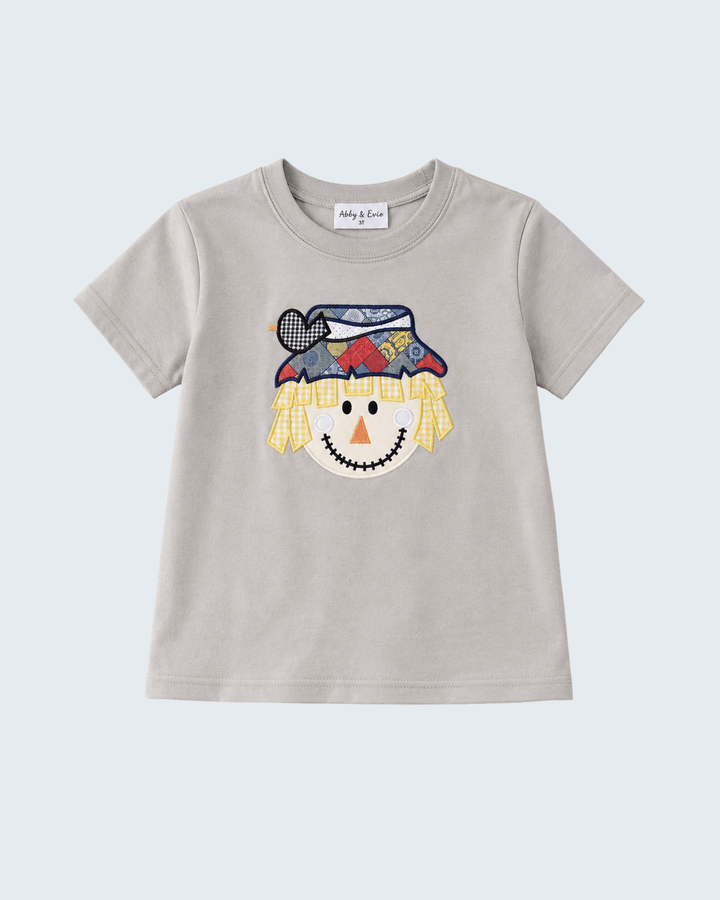 A light gray short-sleeve t-shirt for kids, featuring a colorful embroidered scarecrow face on the front. The shirt is displayed flat against a light gray background.