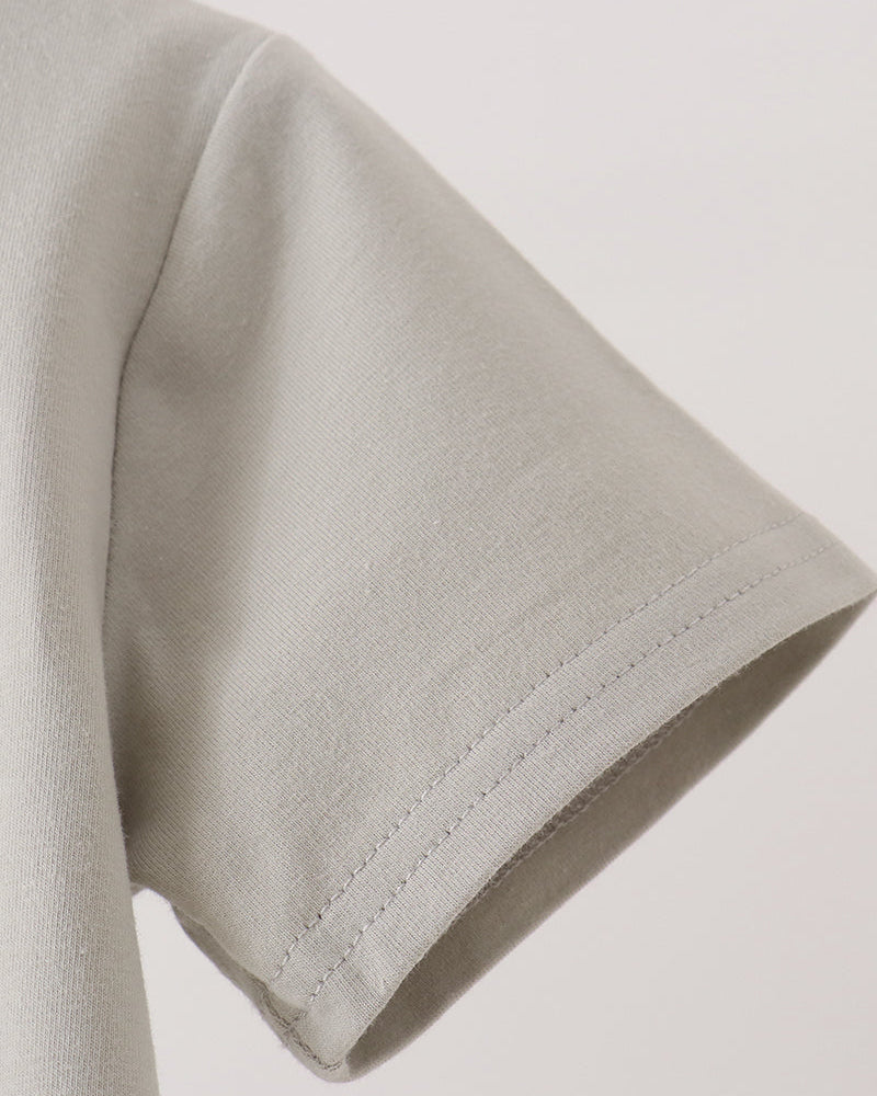 Close-up detail of a short-sleeve t-shirt sleeve showing the stitched cuff on a light gray fabric, set against a plain off-white background.