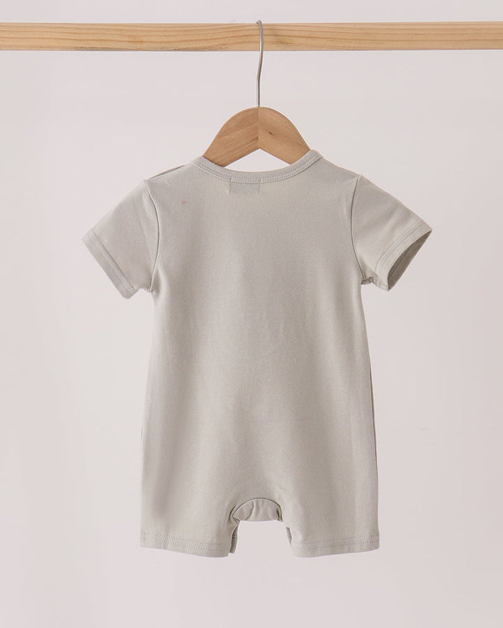 A light gray short-sleeve baby romper hanging on a wooden hanger from a wooden clothes rack against a plain off-white background.