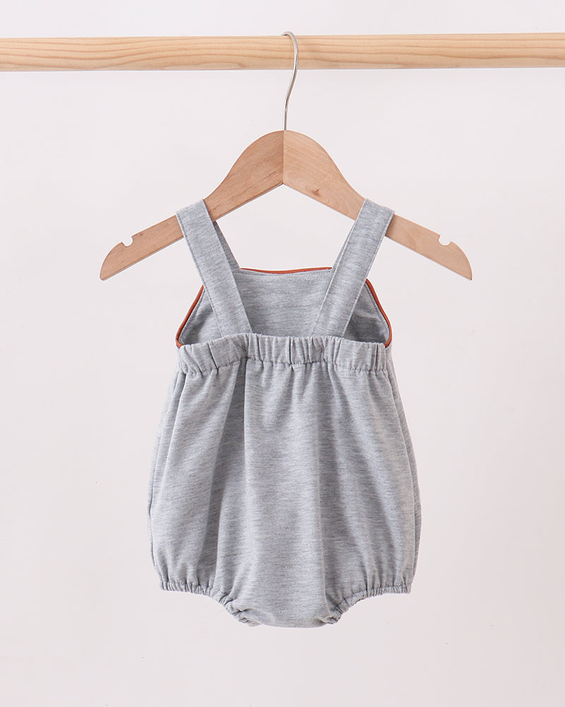 Gray baby romper with straps on a wooden hanger against a white background
