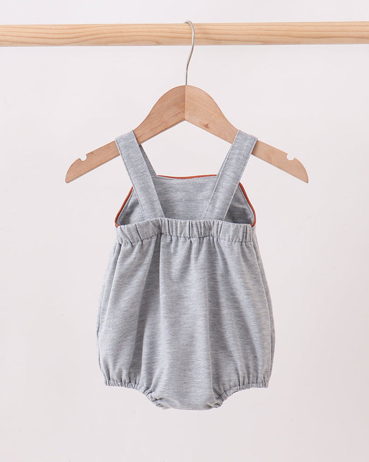 Gray baby romper with straps on a wooden hanger against a white background