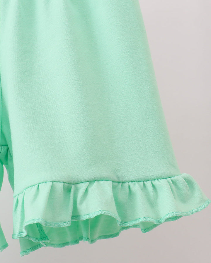 Mint green shorts with ruffled hem on a light gray background