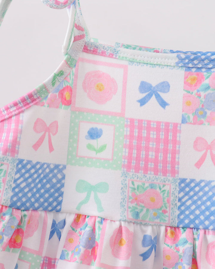 Colorful patchwork dress with floral and bow patterns on a white background