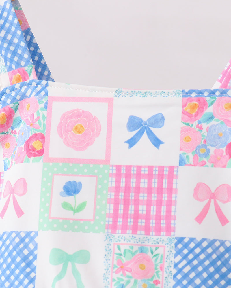 Patchwork swimsuit with floral and bow patterns on a light background
