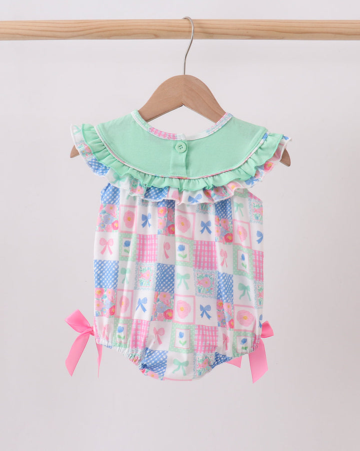 Baby romper with checkered pattern and green collar on a hanger against a white background