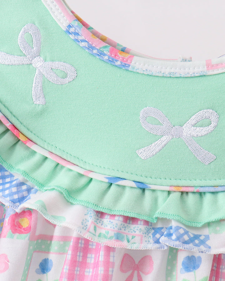 Pastel green fabric with embroidered bows and colorful checkered pattern