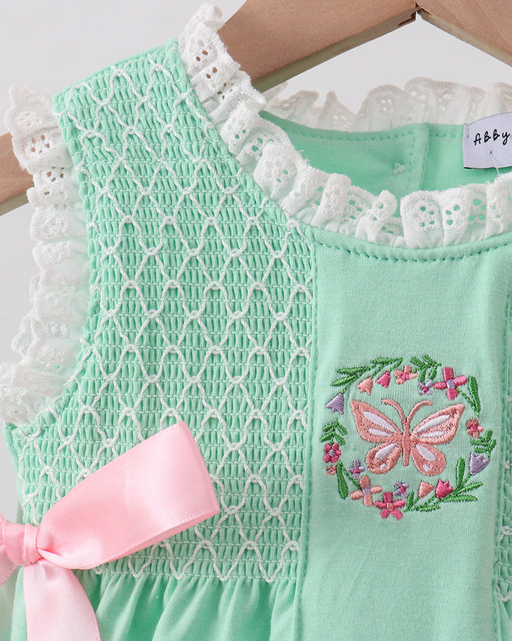Green romper with white lace trim and butterfly design on a hanger
