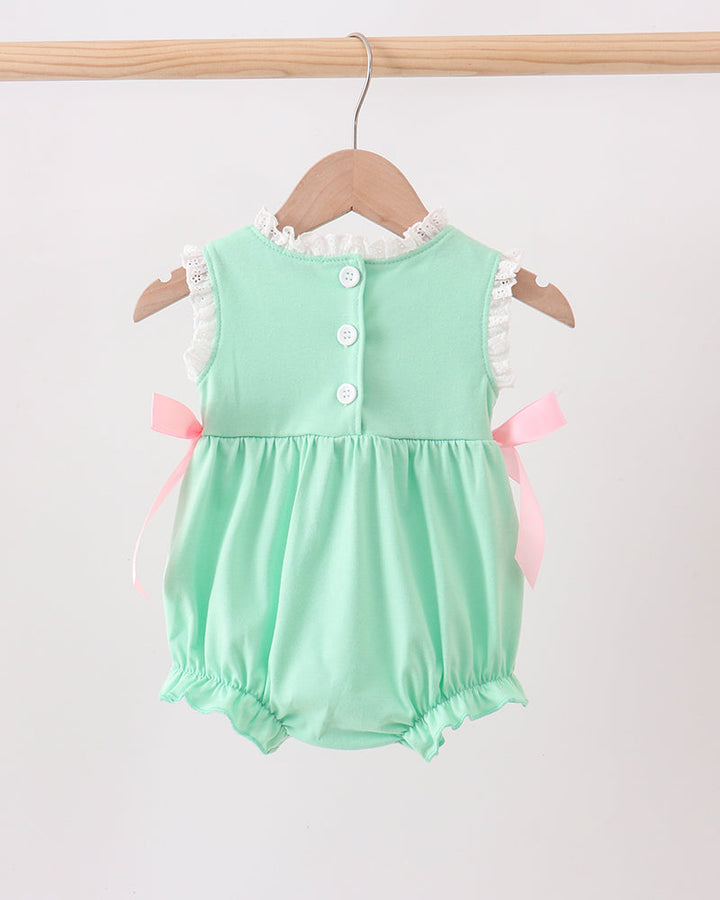Mint green baby romper with pink bows on a wooden hanger against a white background