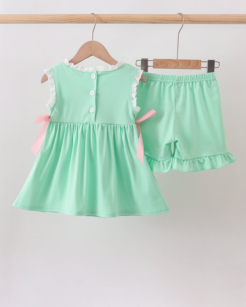 Mint green dress and shorts set on hangers against a light gray background