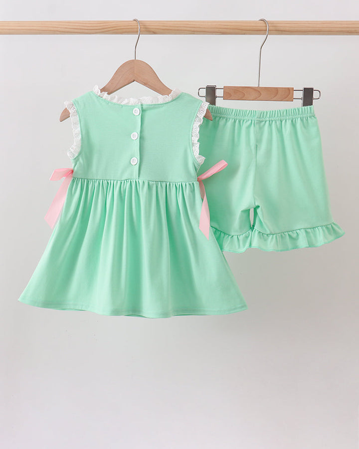 Mint green dress and shorts set on hangers against a light gray background
