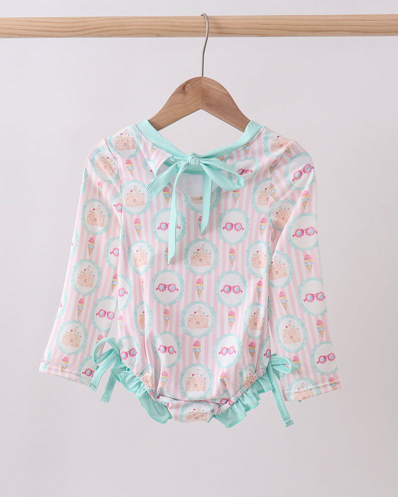 Rashguard with floral pattern and ruffles on a wooden hanger against a white background