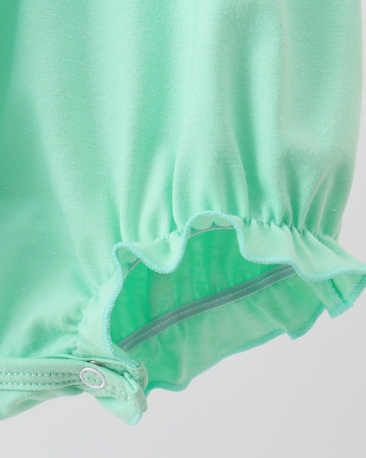 Close-up of mint green baby shorts with an elastic ruffled leg opening and a snap button closure.