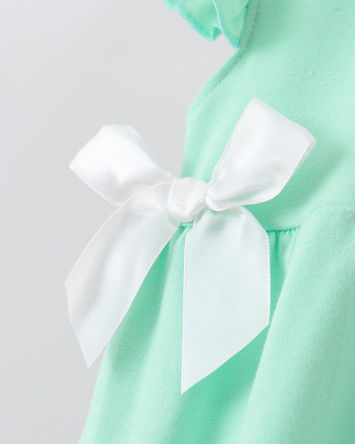 Close-up of a mint green garment with a large white satin bow detail on the front.