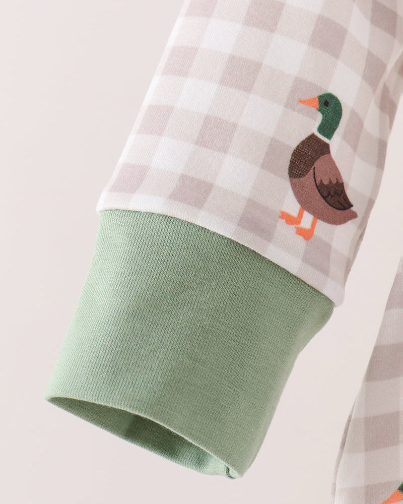 Close-up of a long-sleeve garment sleeve with a white and beige gingham upper section, a sage green ribbed cuff, and a small embroidered duck motif on the sleeve.