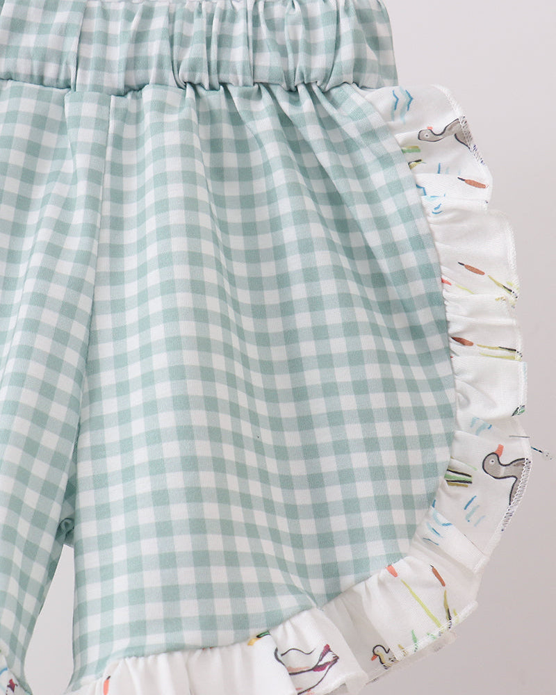 Green checkered shorts with a colorful ruffled edge on a light gray background