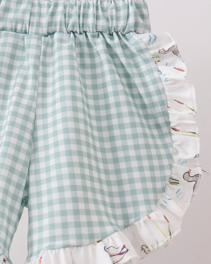 Green checkered shorts with a colorful ruffled edge on a light gray background