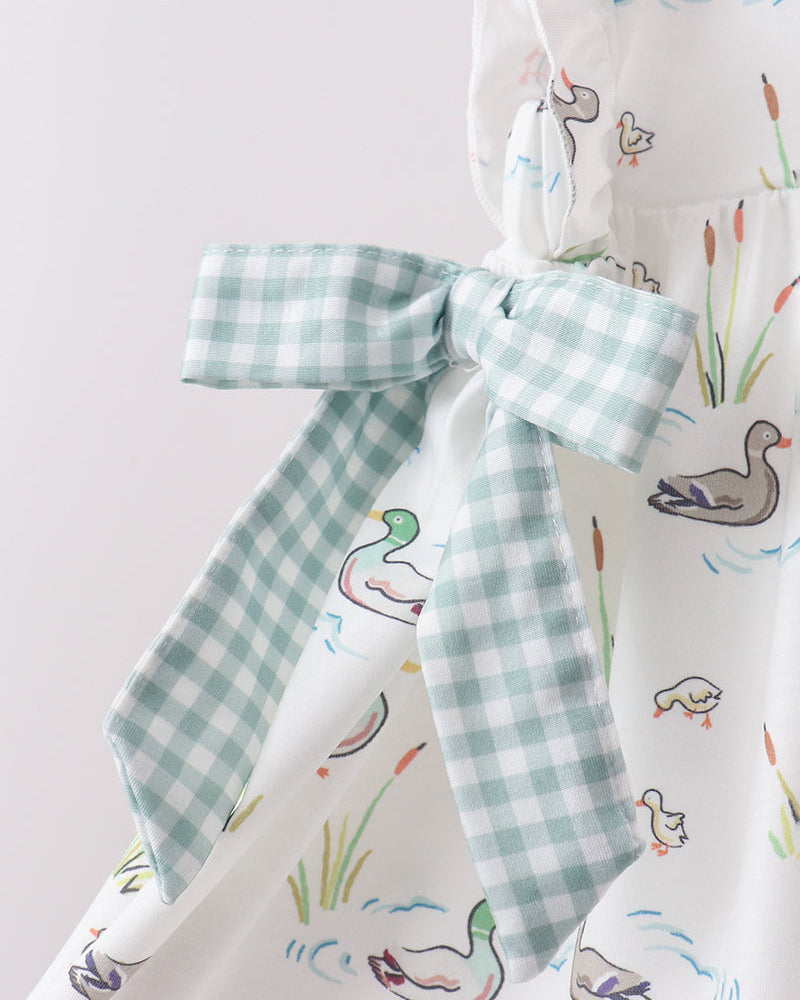 Fabric with duck pattern and a green checkered bow on a light gray background