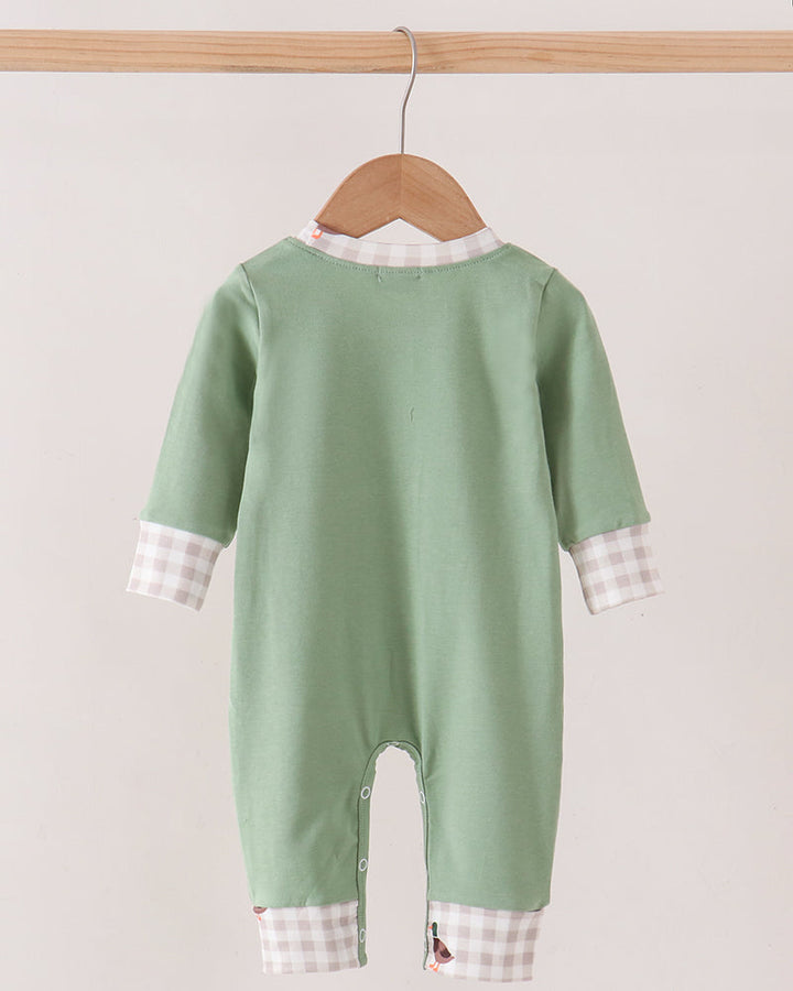 A baby long-sleeve footless jumpsuit in sage green, hanging on a wooden hanger. The jumpsuit features a white and pink gingham check patterned collar and cuffs, shown against a plain light beige background.