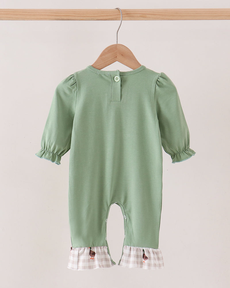 A sage green baby jumpsuit with short puff sleeves and a white-and-beige gingham ruffle hem, hanging on a wooden hanger against a light beige background.