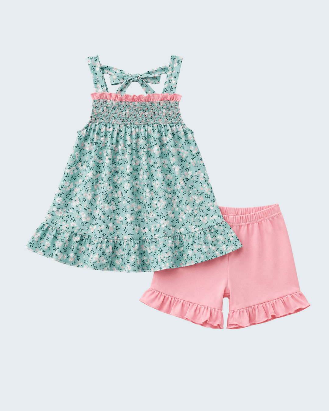 A toddler girl's two-piece summer outfit set featuring a smocked sleeveless dress in a mint green and white floral print with a pink ruffle trim, paired with solid pink ruffle-trimmed shorts, shown on a light gray background.