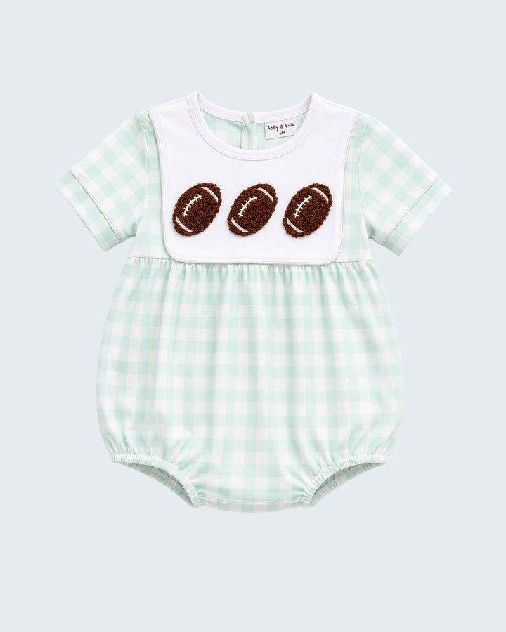 A baby short-sleeve romper in a light mint green and white gingham pattern, featuring a solid white bib-style chest panel with three brown football appliqués, photographed on a light gray background.