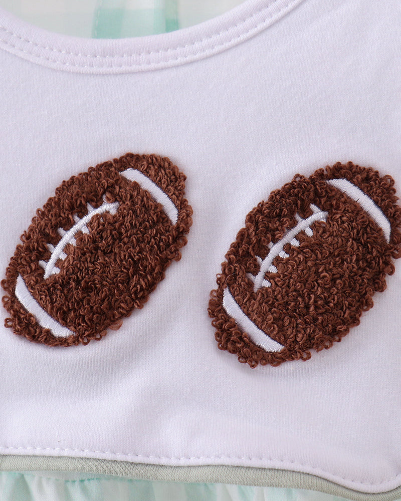 Close-up of a white baby top with two brown embroidered football appliqués on the chest and a small neck label reading Abby &amp; Co 6M.