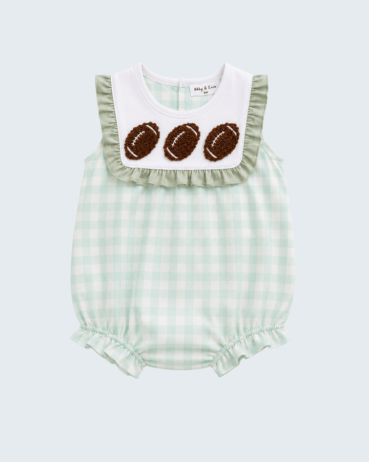 A baby romper in a light green and white gingham pattern, featuring a white bib collar with ruffles and three brown embroidered footballs, set against a solid light gray background.