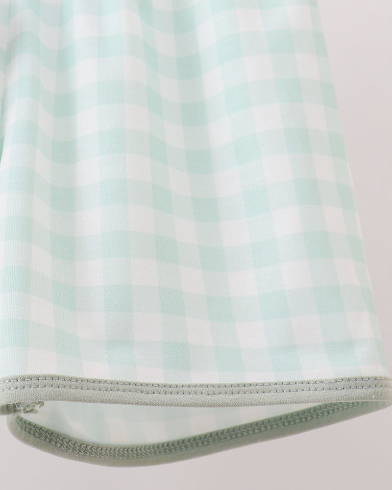 Close-up of a mint green and white gingham check fabric item with a zipper along the bottom edge, shown against a light neutral background.