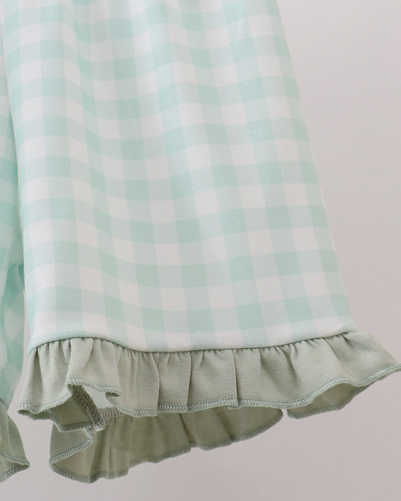 Close-up of a mint green and white gingham check fabric with a ruffled hem, shown against a plain light background.