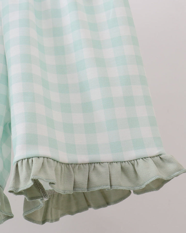 Close-up of a mint green and white gingham check fabric with a ruffled hem, shown against a plain light background.