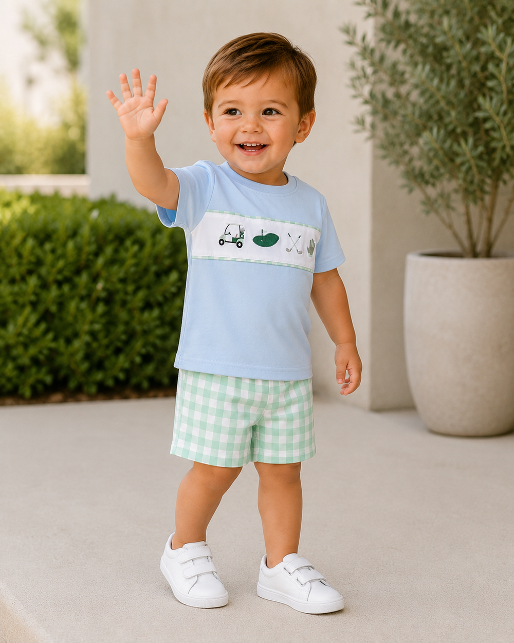 Toddler boy wearing light blue T-shirt with green tractor embroidery and mint gingham shorts