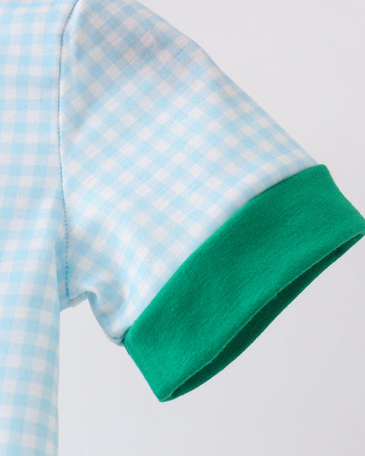 Close-up of a blue and white checkered shirt with green trim on a light gray background