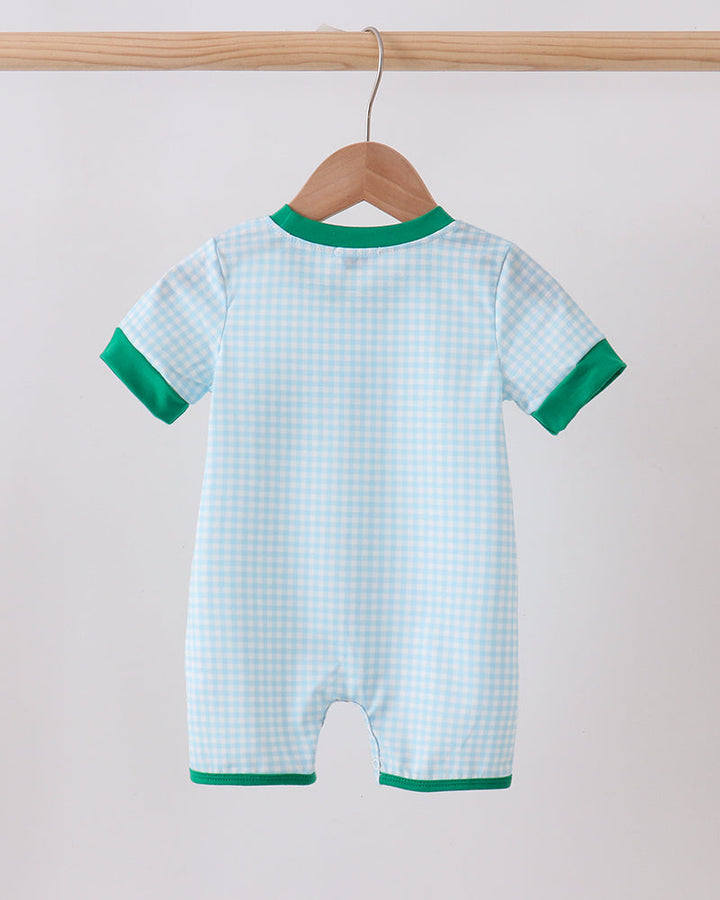 Baby romper with green trim hanging on a wooden hanger against a light background