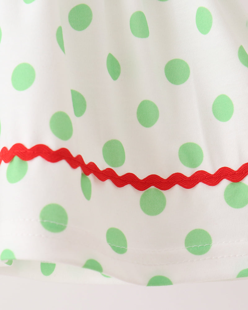 Green polka-dot fabric with red ruffled trim on white dress top