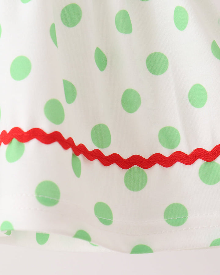 Green polka-dot fabric with red ruffled trim on white dress top