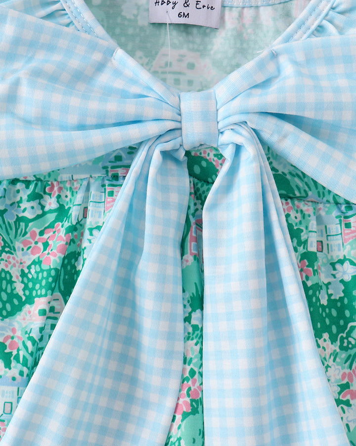 Close-up of a dress with a bow detail and floral pattern, on a hanger with &