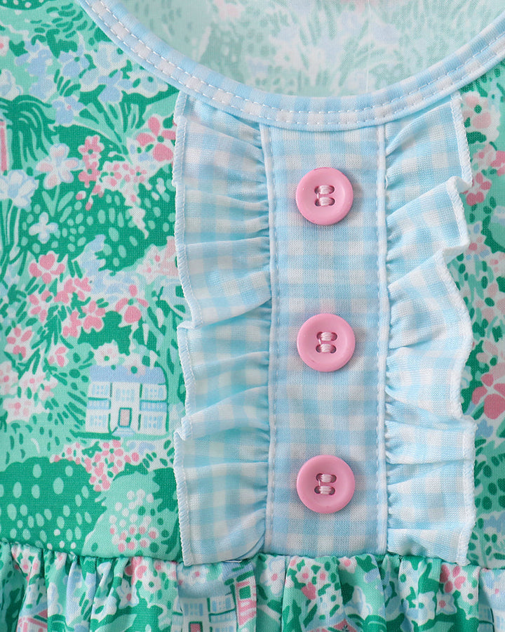 Close-up of a dress with floral pattern and pink buttons on a green background