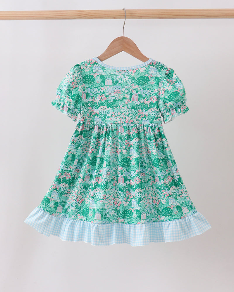 Green floral dress hanging on a wooden hanger against a white background
