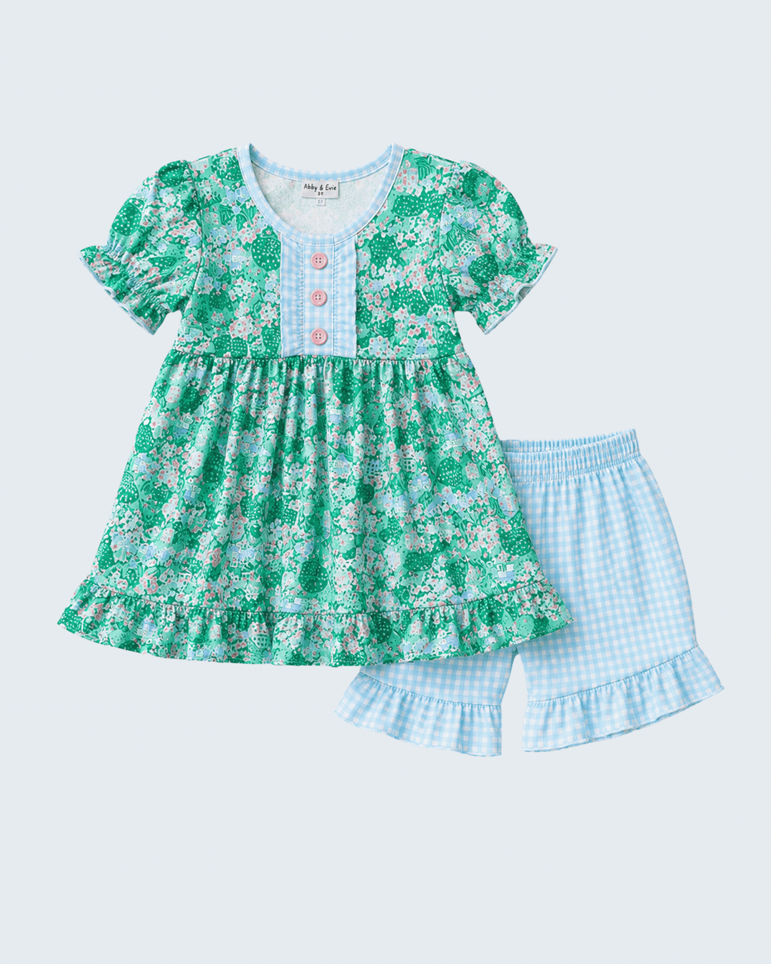 Green floral dress with ruffled details and matching shorts on a light blue background